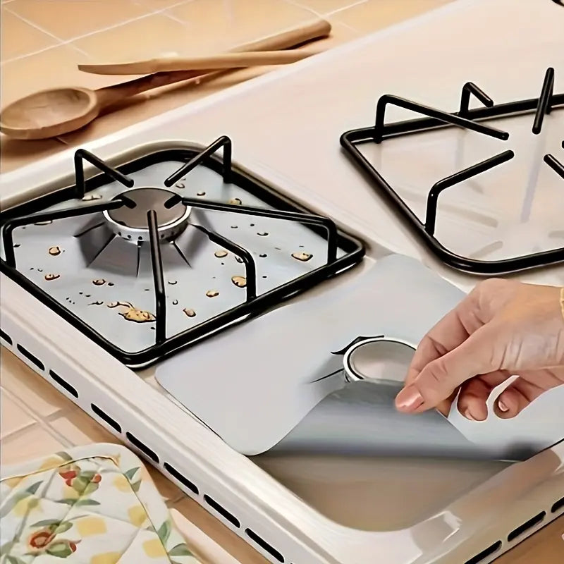 A silver gas stove liner being lifted from a clean cooktop
